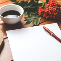 内容编辑在书架旁的木质书桌前查阅合规资料并做批注，桌上摊开笔记本与荧光笔，午后斜射的暖色自然光
